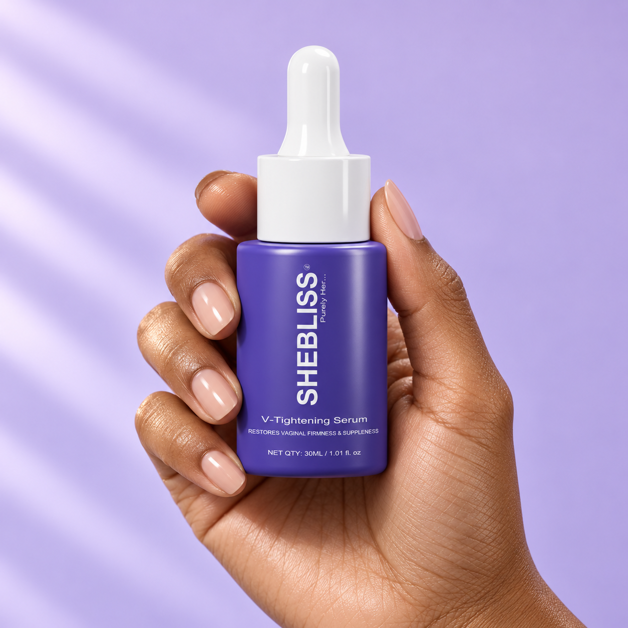 SheBliss V-Tightening Serum held in a hand against soft lilac